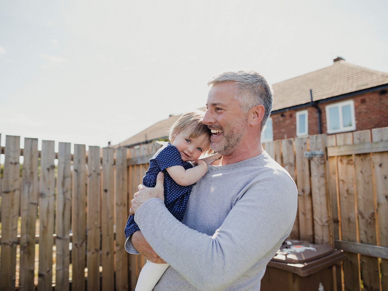 Man som kramar en bebis utomhus.