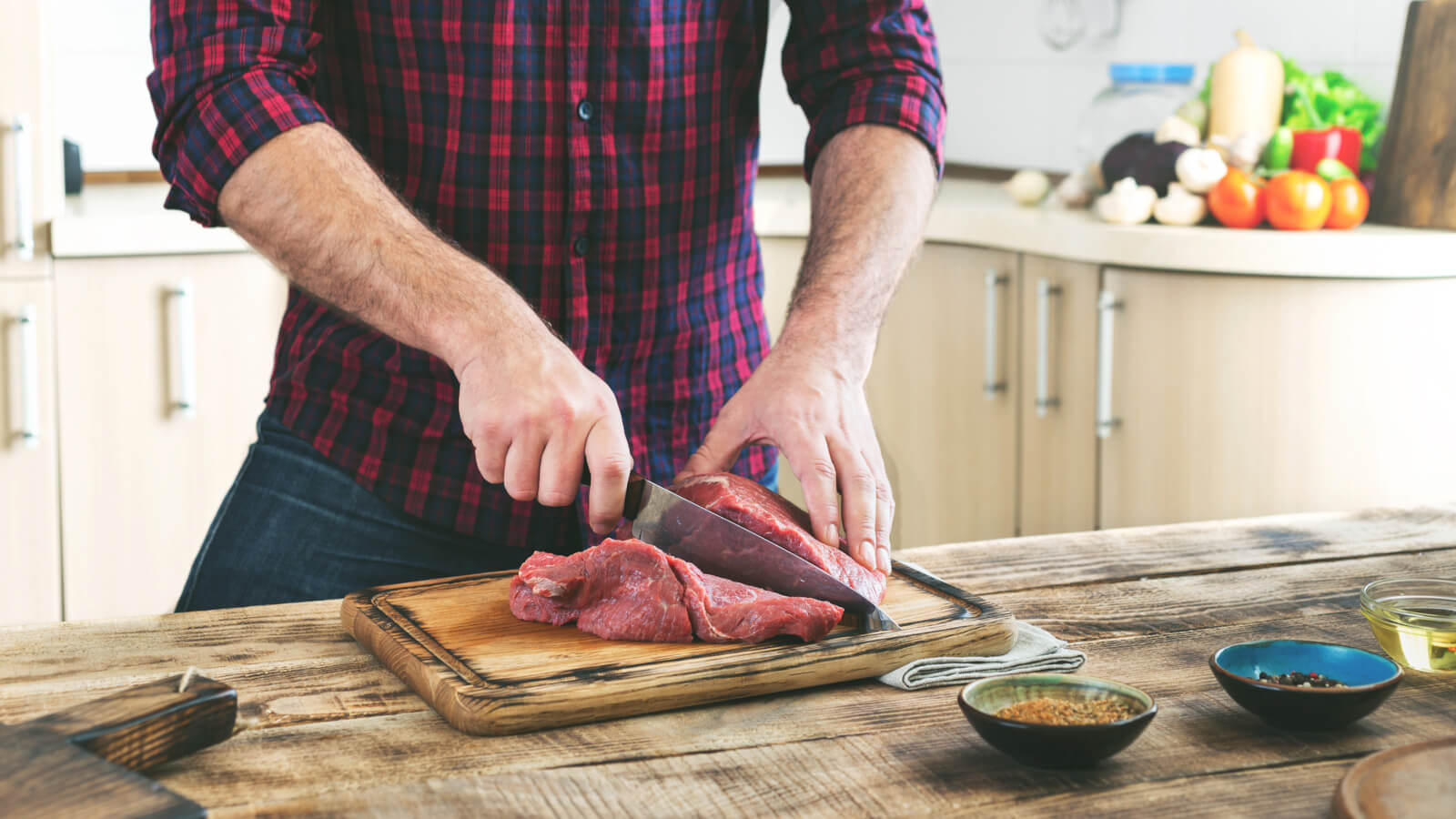 Man står i köket och skär kött i närbild