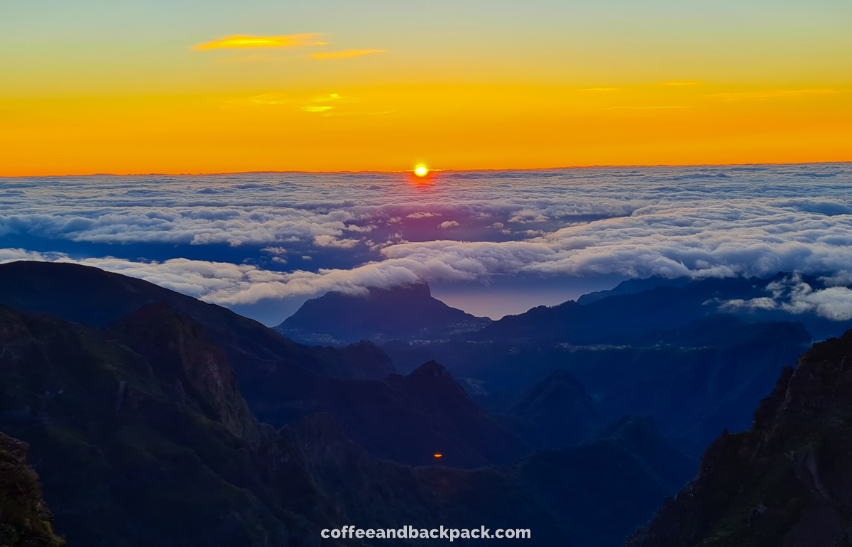 Pensive hiker using smart phone on mountain peak during sunrise at