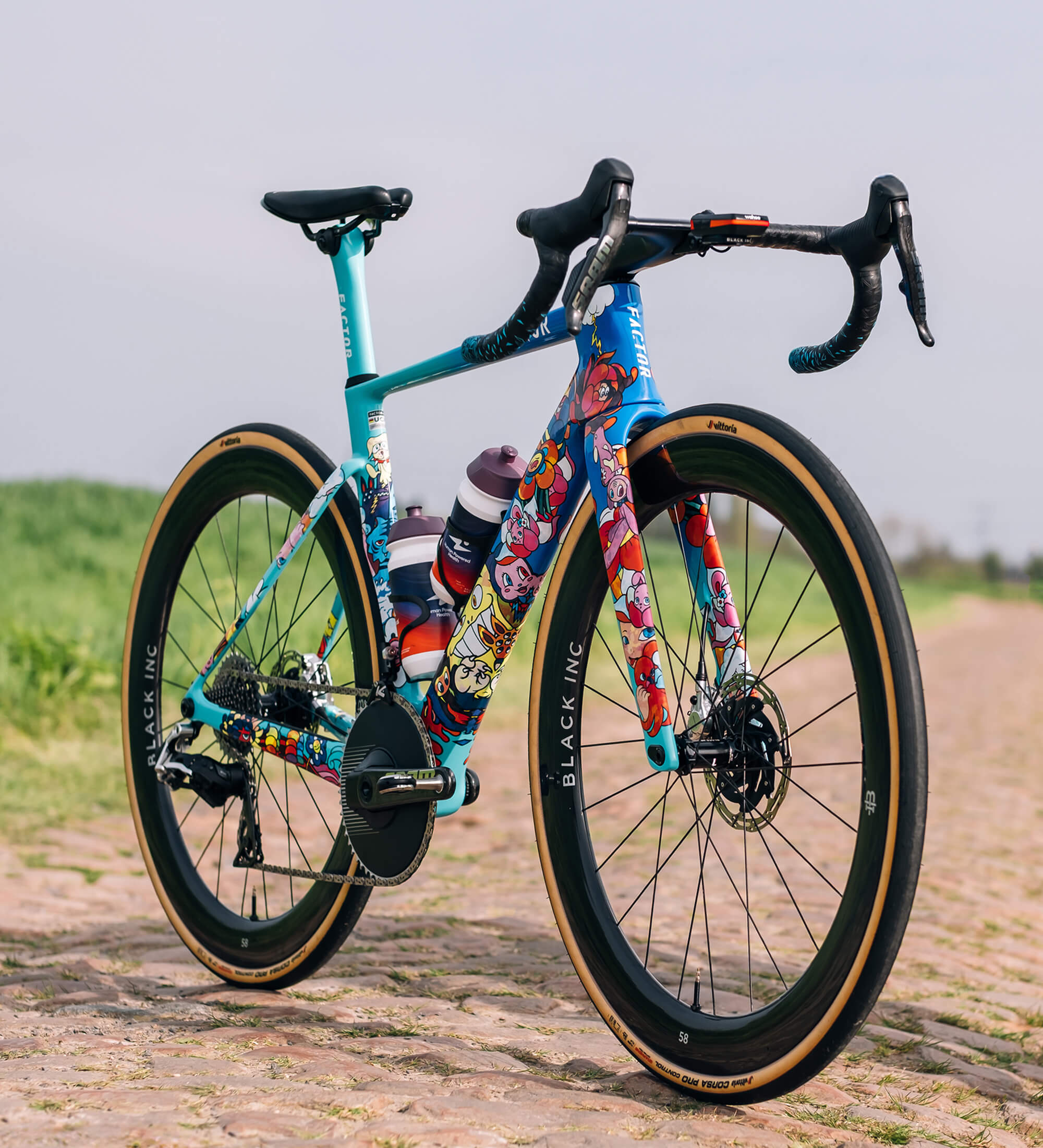 MONZA VEXX Edition angled forward sitting on a sunny cobbled road somewhere in northern France with green grass and gloomy skies in the background.