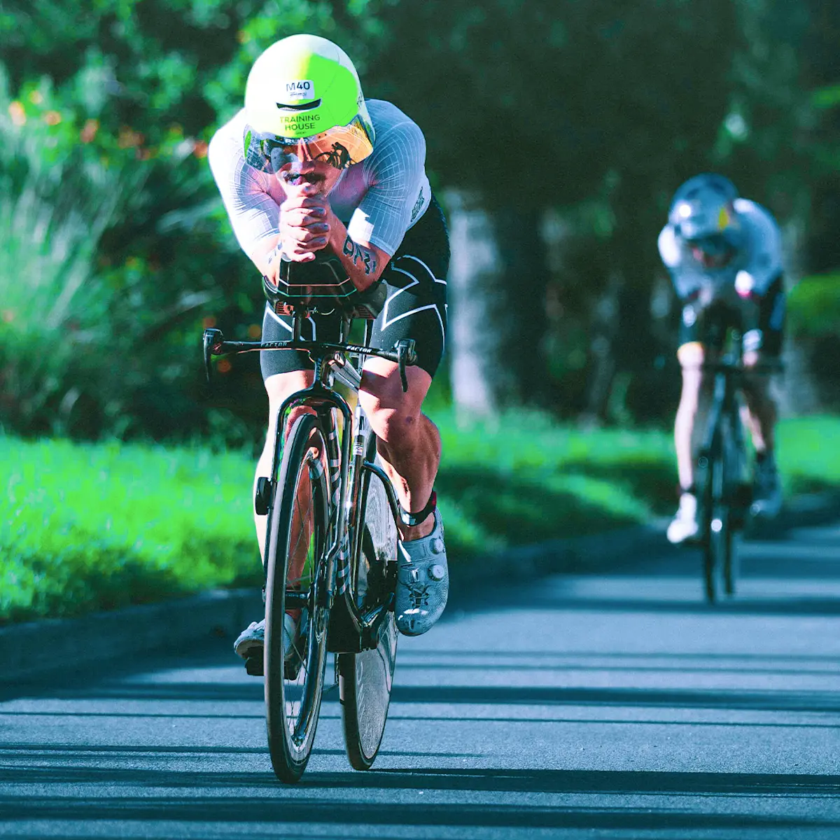 Front action shot of a Factor athlete racing on his ONE SP in a super aero position. He is distancing a rider behind.