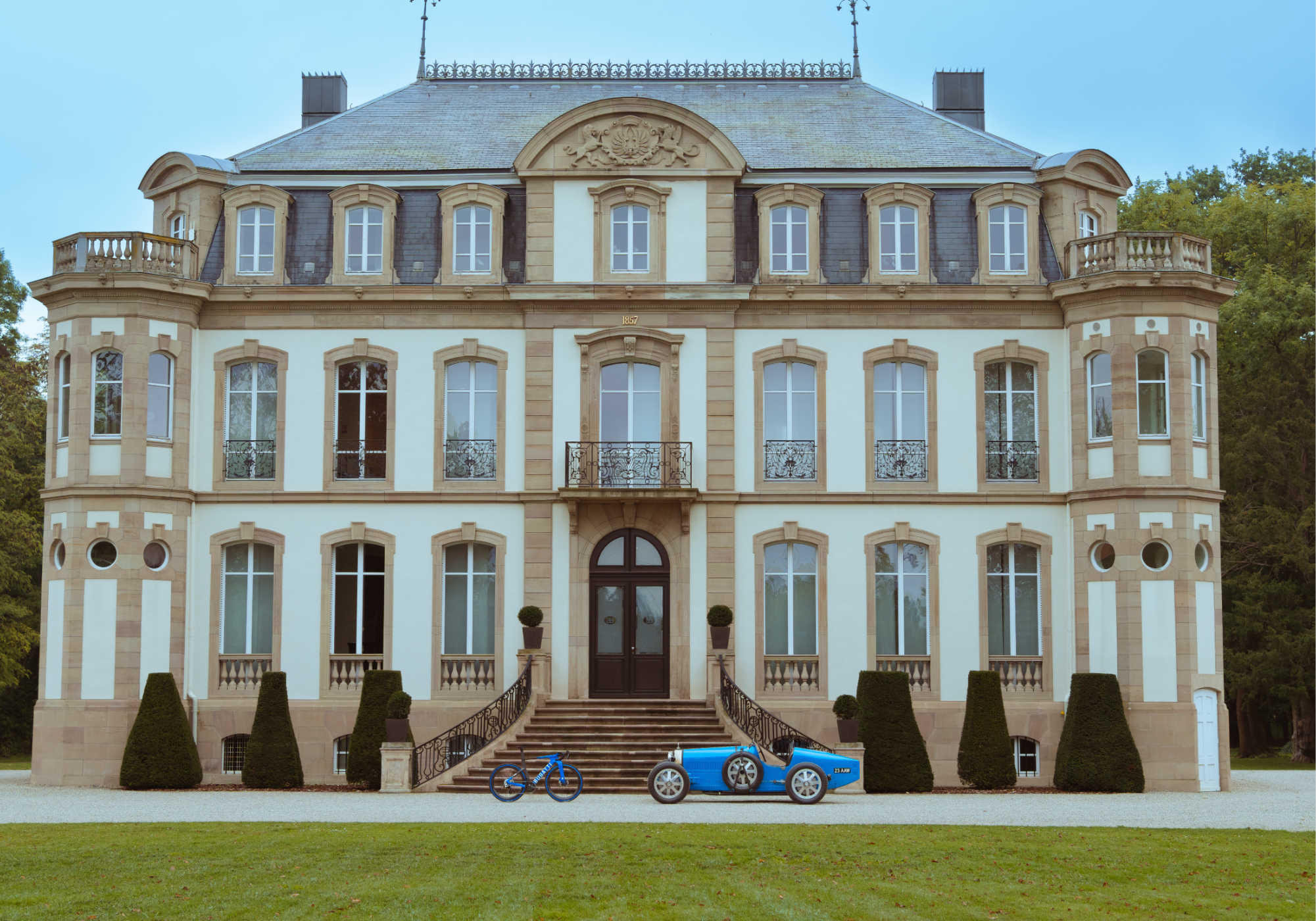 Side view of a Bugatti Factor ONE facing a Bugatti Type 35 automobile standing in front of the steps of the Chateau Saint Jean, the home of Bugatti.