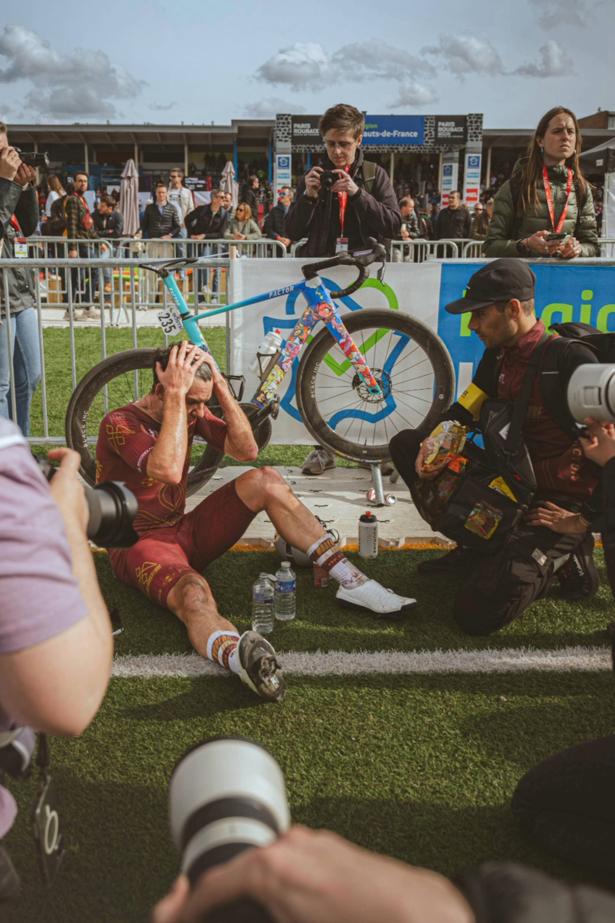 Modern Adventure Pro Cycling rider sitting down next to the MONZA VEXX Edition in the velodrome surrounded by photographers after finishing Paris Roubaix 2026
