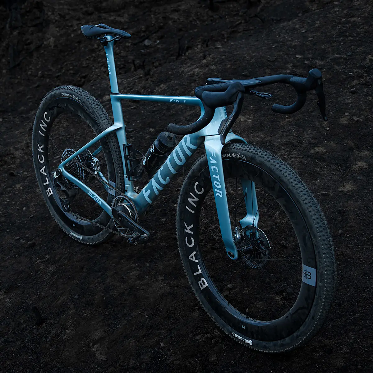 Quarter-turn drivetrain side view of the ELARA in Virescent Blue complete with Black Inc 64 Gravel wheels. Dark lighting.