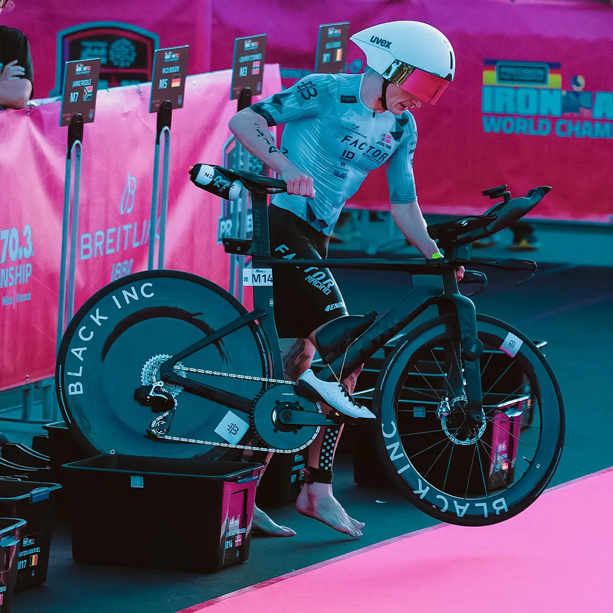 Side view of a Factor athlete grabbing his ONE SP at the T1 point of a triathlon. Complete with Black Inc 62 and ZERO wheels.