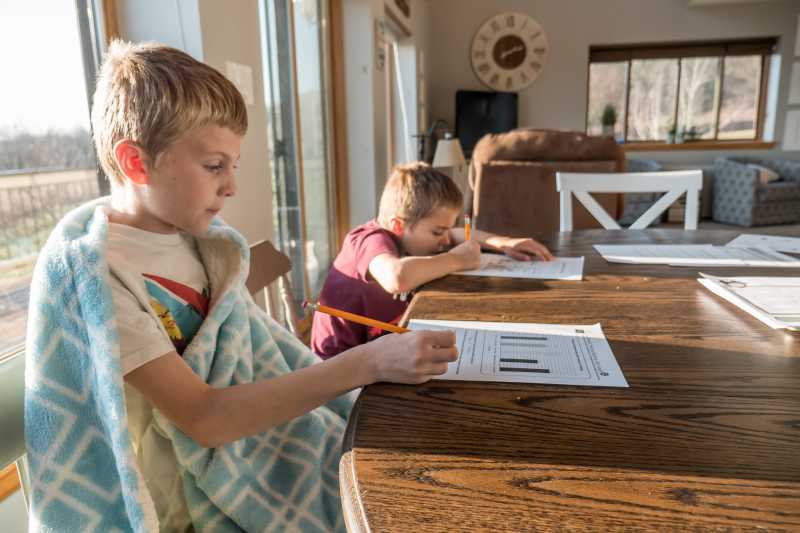 Photo of two children doing homework at the dining table.