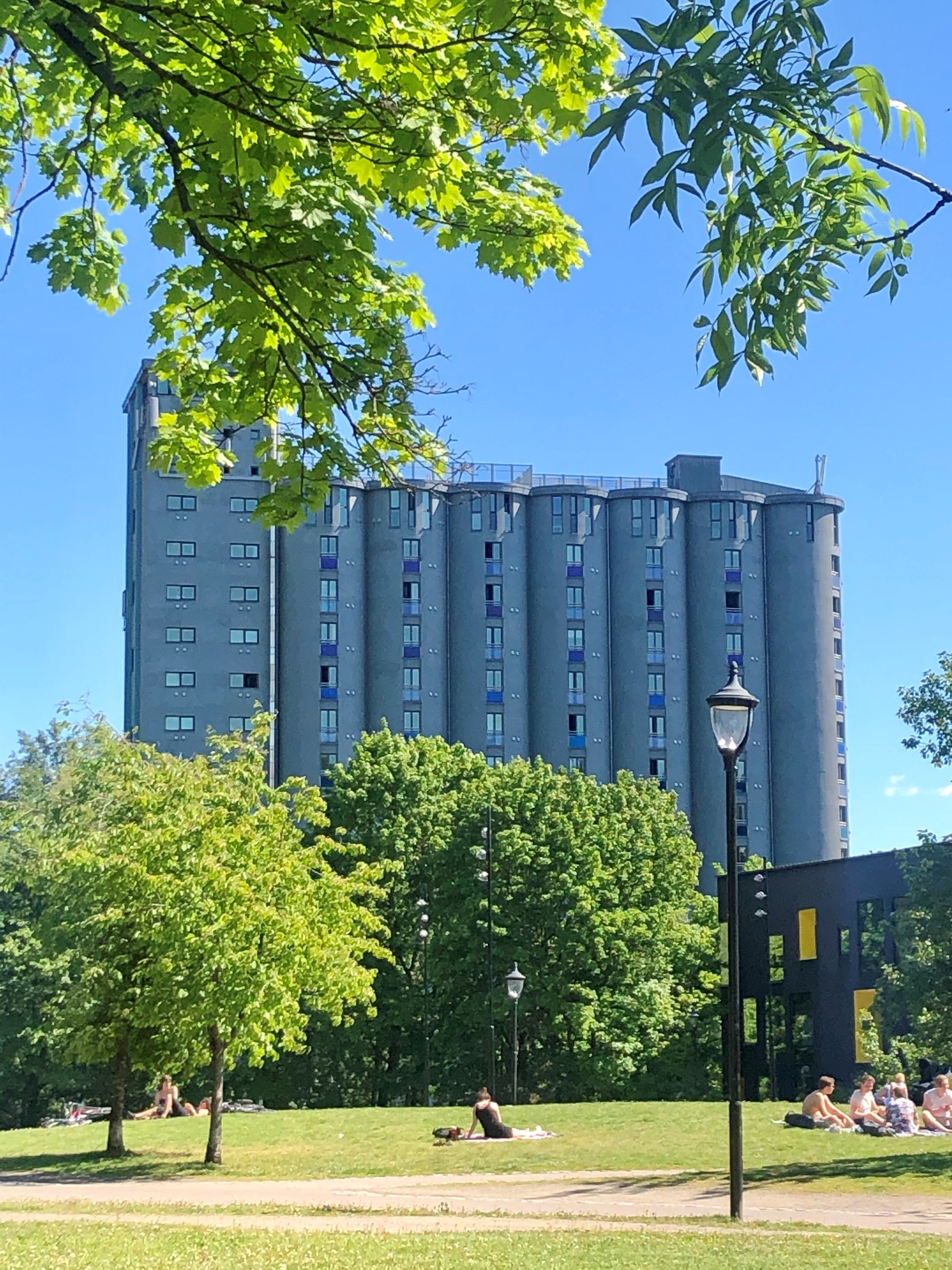 Et bilde av Grünerløkka Studenthus. Bildet viser et høyt bygg som har form som flere kornsiloer som står inntil hverandre. I forgrunnen av bildet er det et parkområde. 