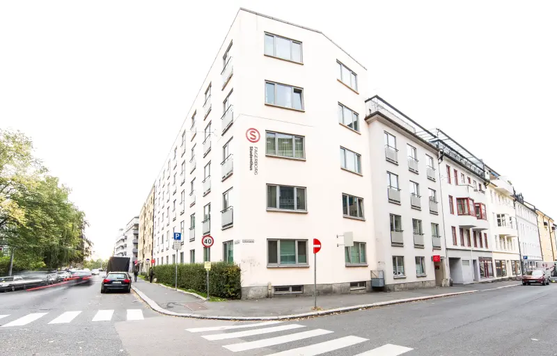 A picture of Fagerborg Student House. The picture shows a white high-rise building located right by a road intersection.