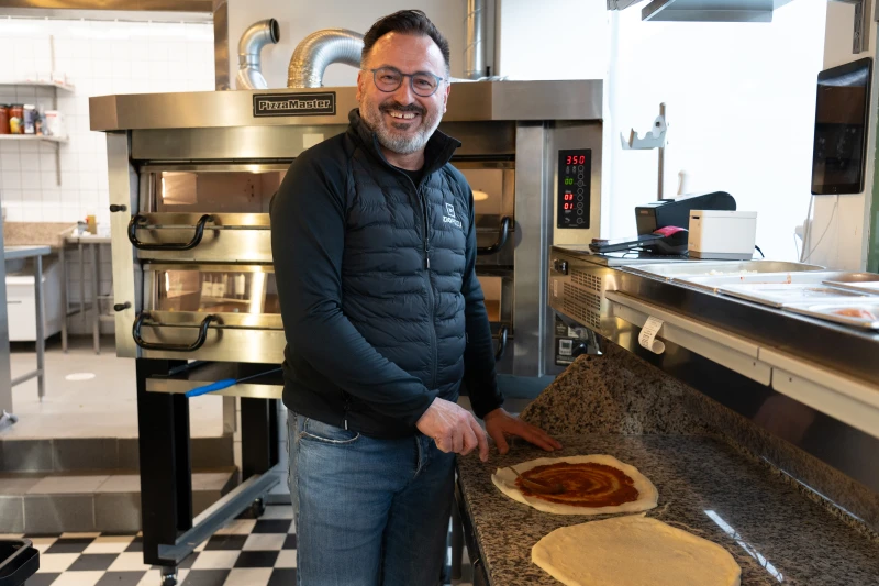 Picture of a man smiling while making pizza