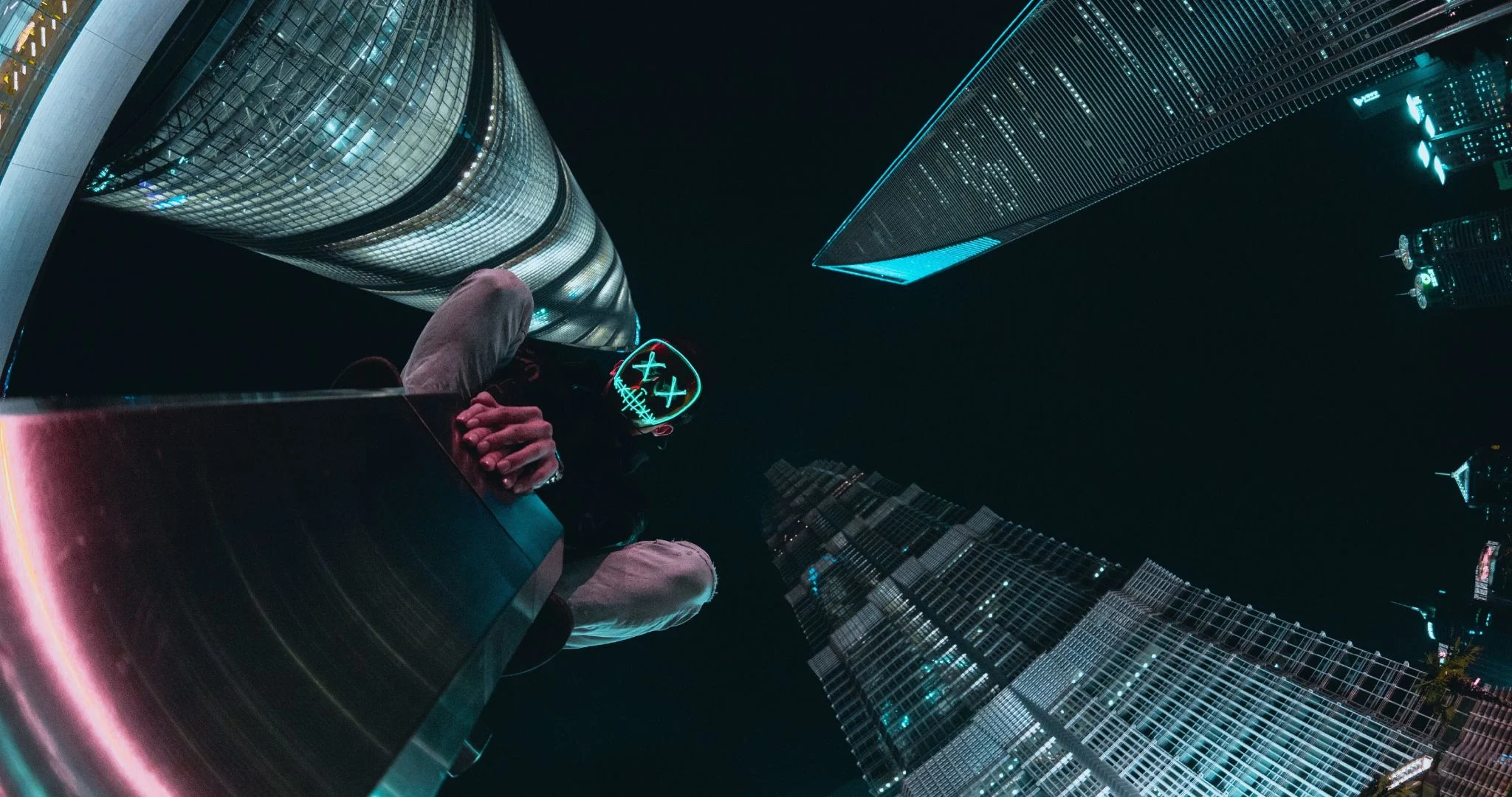 A person crouched on a post in a city, with POV looking up at skyscrapers. Source: Mahosadha Ong / Unsplash