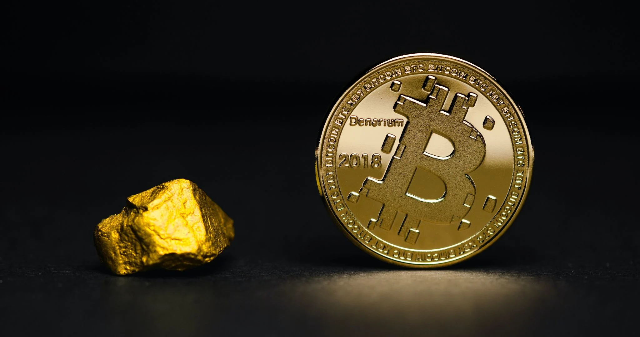 A physicla bitcoin, next a slab of gold.