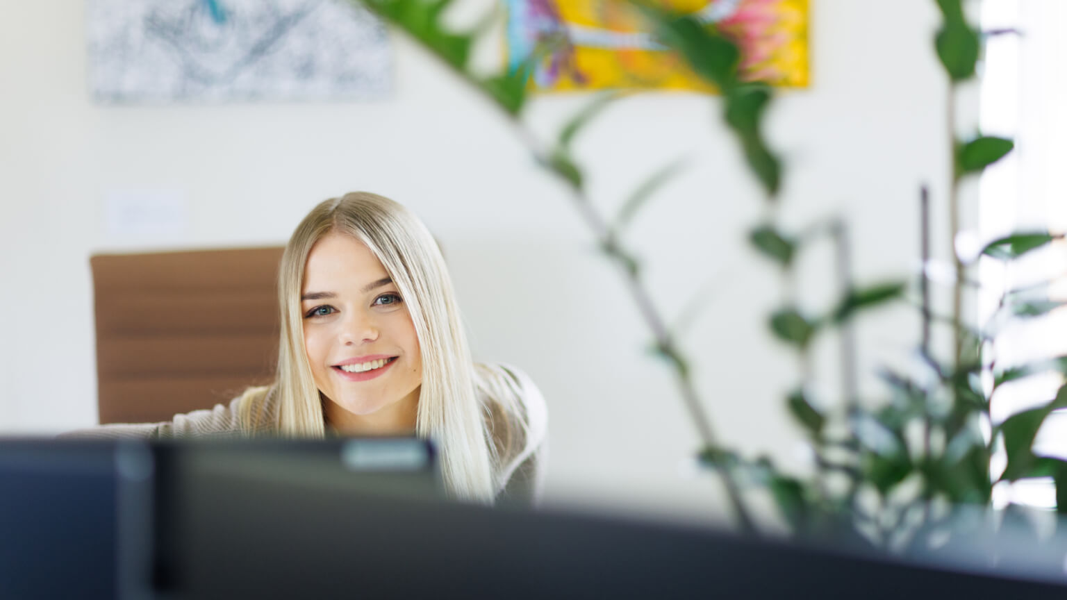 woman smiling from behind a computer
