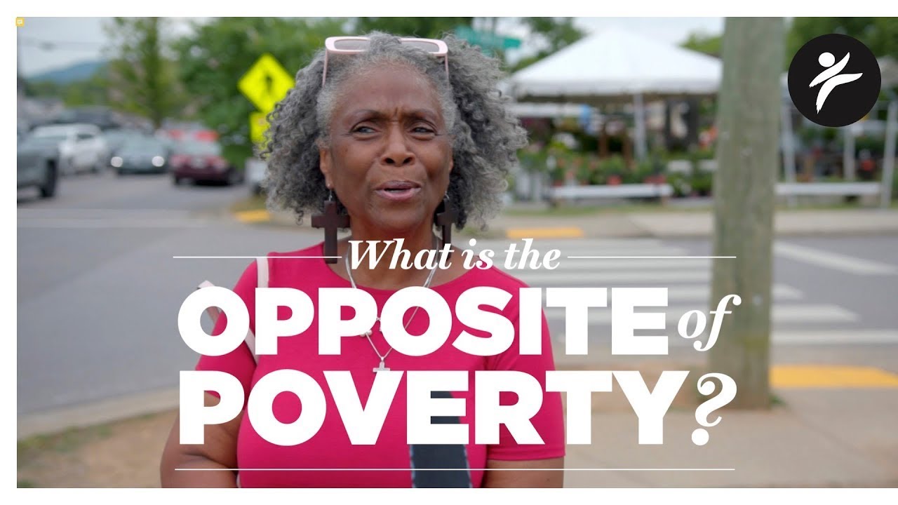 A woman in a bright pink t-shirt looks at the camera with the words "What is the Opposite of Poverty?" overlayed in white text.