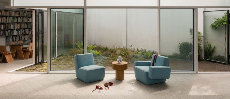 A lifestyle image of a lounge scene featuring Hunk Lounge Chair, Hunk Lounge Chair with Armrests, and Stump Side Table Natural.