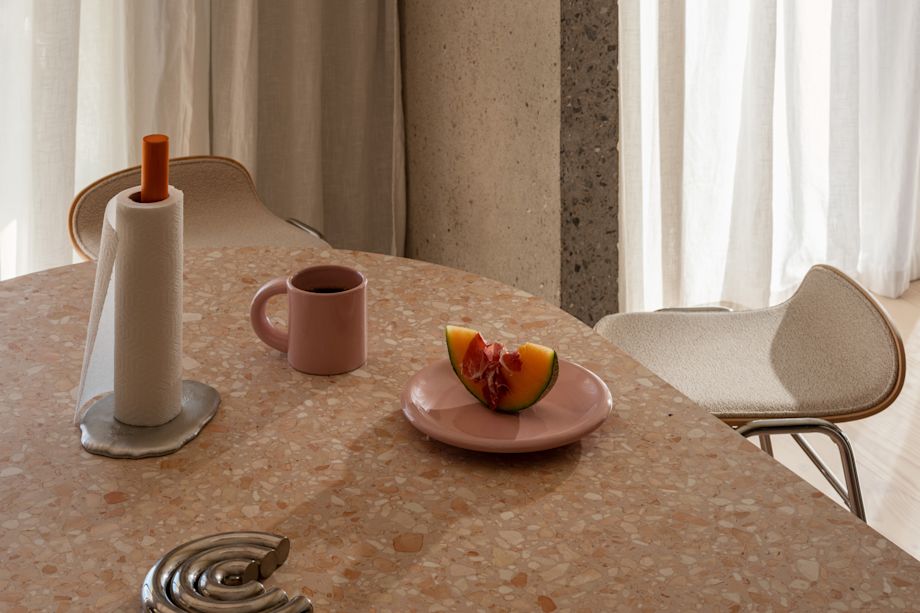 A lifestyle image of a kitchen/dining scene featuring Spill Kitchen Roll Holder, Touchwood Counter Stools, Bronto Mug, and Bronto Plate.