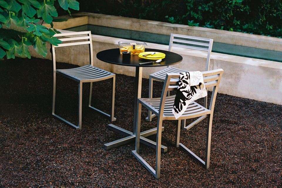 A lifestyle image of an outdoor scene featuring Chop Chairs and Tables in Stainless.