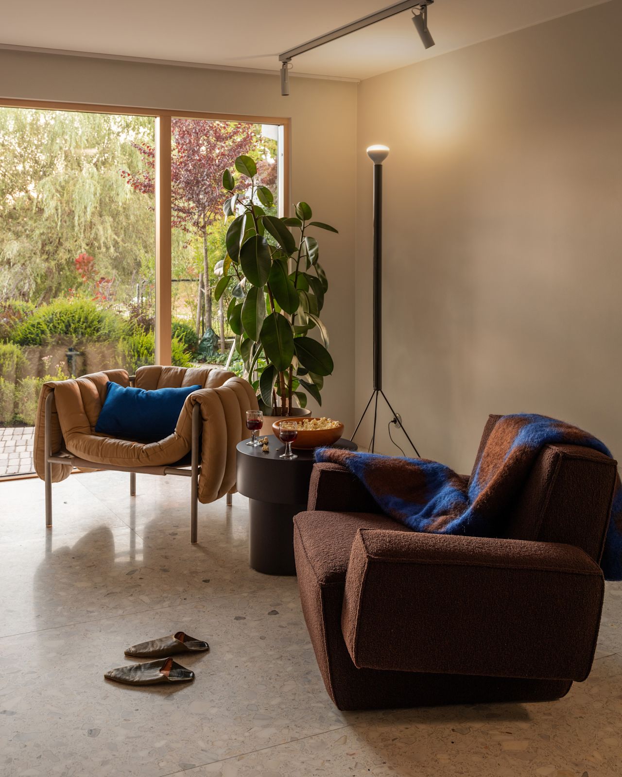 A lifestyle image of a lounge scene featuring Puffy Lounge Chair, Hunk Lounge Chair with Armrests, Storm Cushion Large, Monster Throw, and Stump Side Table.