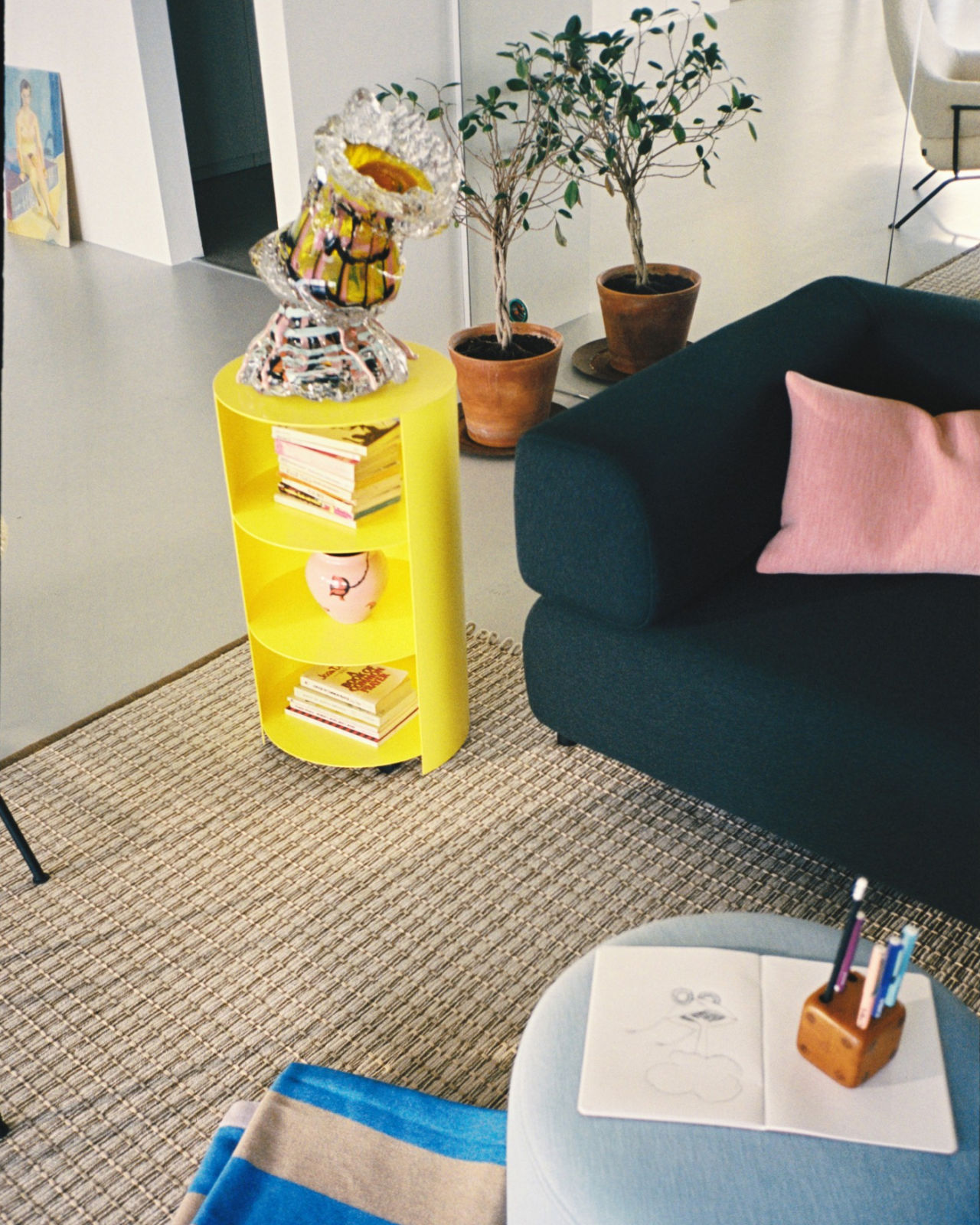 An analog image of a lounge/living room scene featuring Neo Cushion Large, Palo Modular Sofa, Rope Rug, Hide Pedestal, Stripe Throw, and Bon Pouf Round.