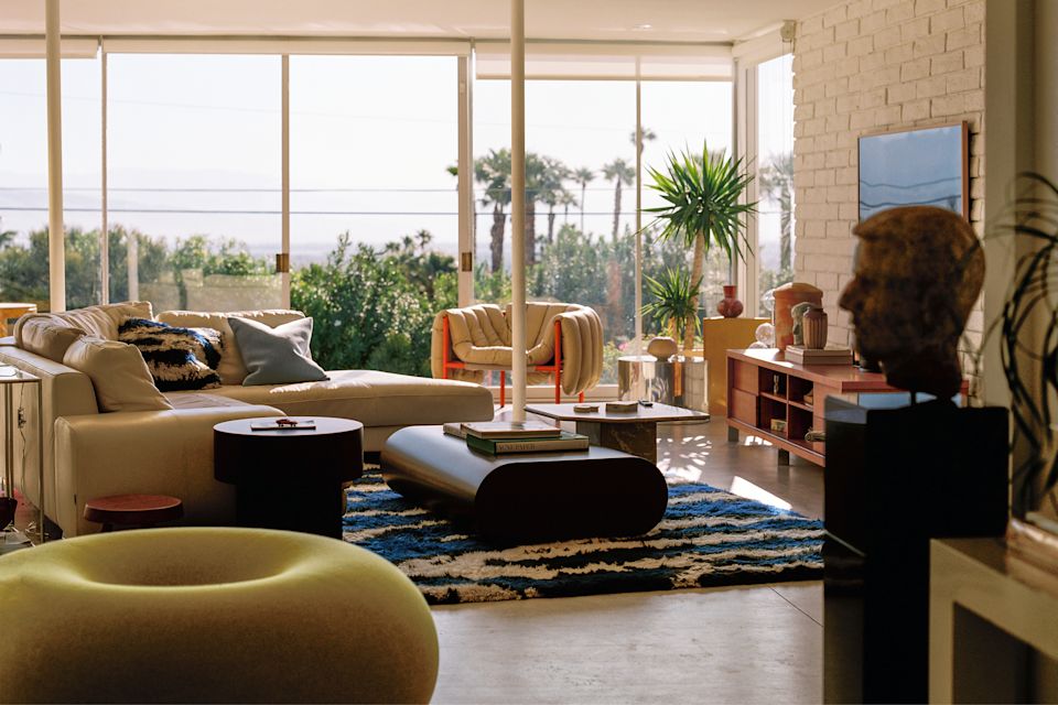 A lifestyle image of a living room scene featuring Puffy Lounge Chair, Stump Coffee Table Large, Monster Rug Extra Large, Velvet Cushion Medium, Boa Pouf, Stump Side Table, and Monster Cushion Medium.