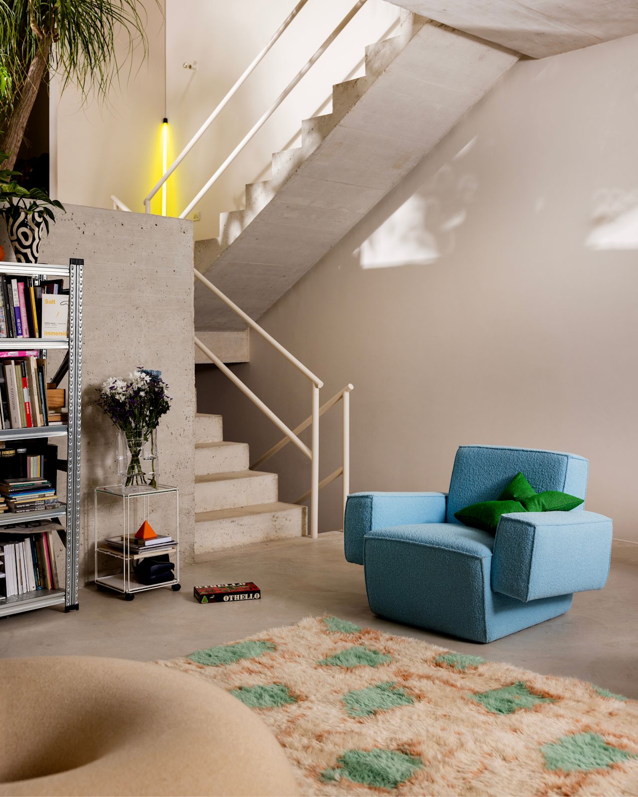 A lifestyle image of a lounge scene featuring Hunk Lounge Chair with Armrests, Boa Pouf, Crepe Cushion Medium, Brute Vase Clear, and Monster Rug.