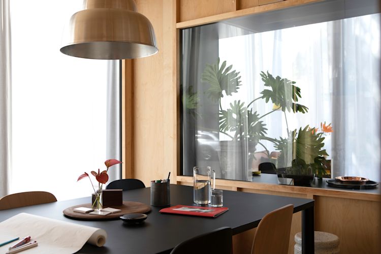 A lifestyle image of a dining scene from the Hem Headquarters in Stockholm, Sweden in 2018 featuring Levels Lamp, Log Table, Touchwood Chairs and Last Stool.