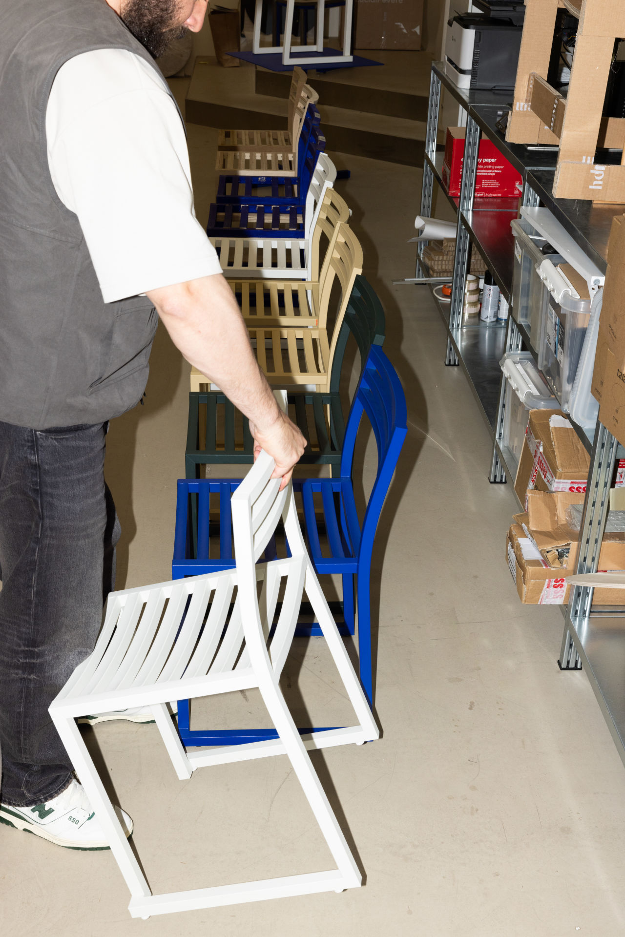 An editorial image from behind the scenes with Philippe Malouin, the designer of Chop Chair and Chop Tables, featuring the Chop Chairs in 4 powder-coated colorways.