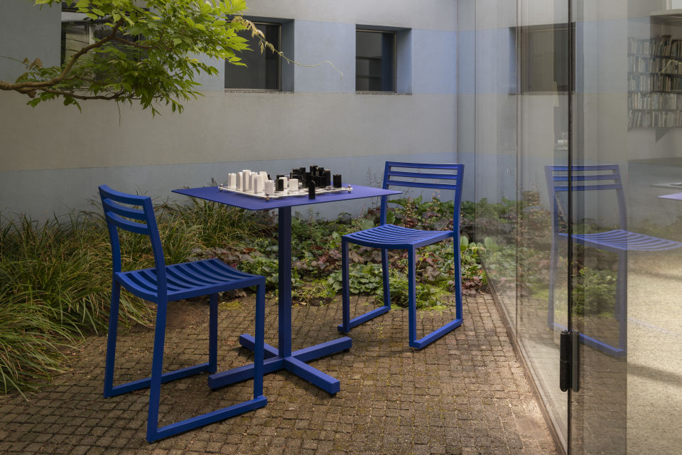A lifestyle image of a patio scene featuring Chop Table Square and Chop Chairs in the shade Ultramarine Blue.