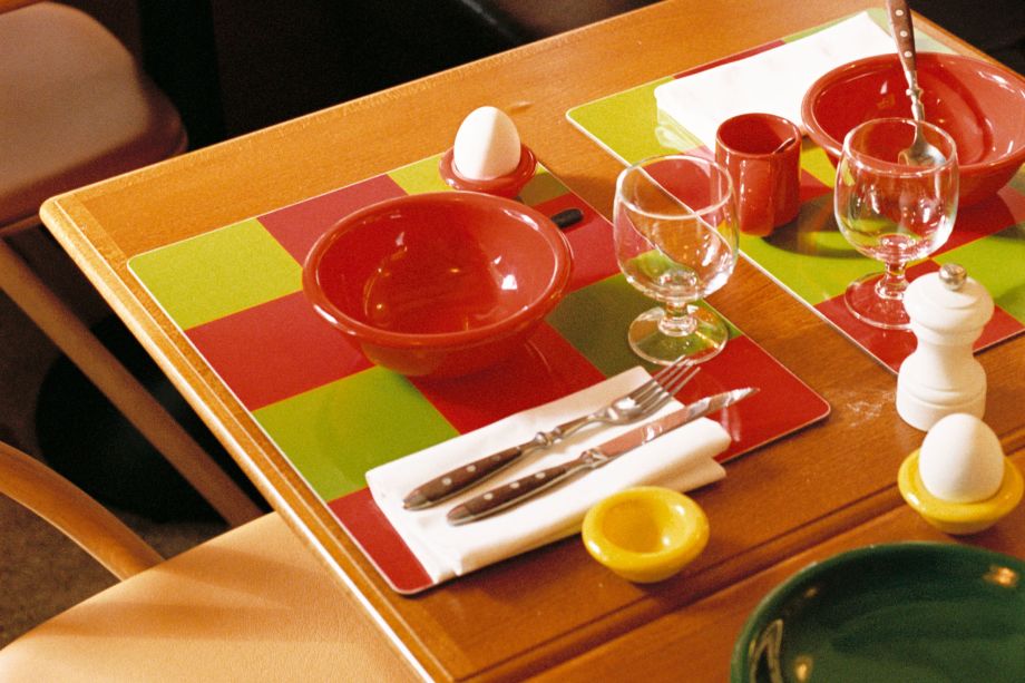 A lifestyle image of a dining scene featuring Bronto Egg Cups, Bronto Bowls, Check Placemats, and Bronto Espresso Cups.