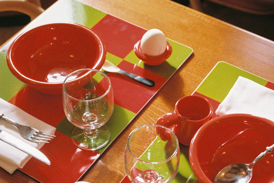 A lifestyle image of a kitchen/dining scene featuring Check Placemats, Bronto Bowls, Bronto Espresso Cups, and Bronto Egg Cups.