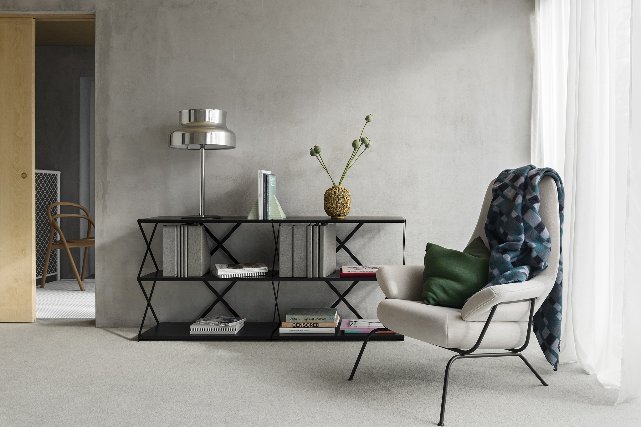 A lifestyle image of a living room scene featuring Hai Lounge Chair, Vienna Throw, and Lift Shelf.