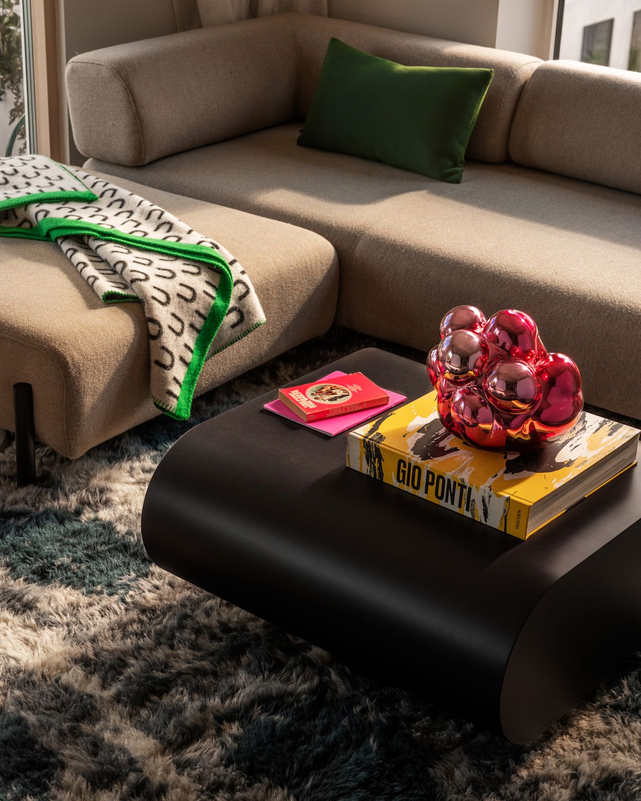 A lifestyle image of a living room / lounge scene featuring Palo Modular Sofa, Arch Throw, Stump Coffee Table Medium, Moln, Neo Cushion Large, and Monster Rug.