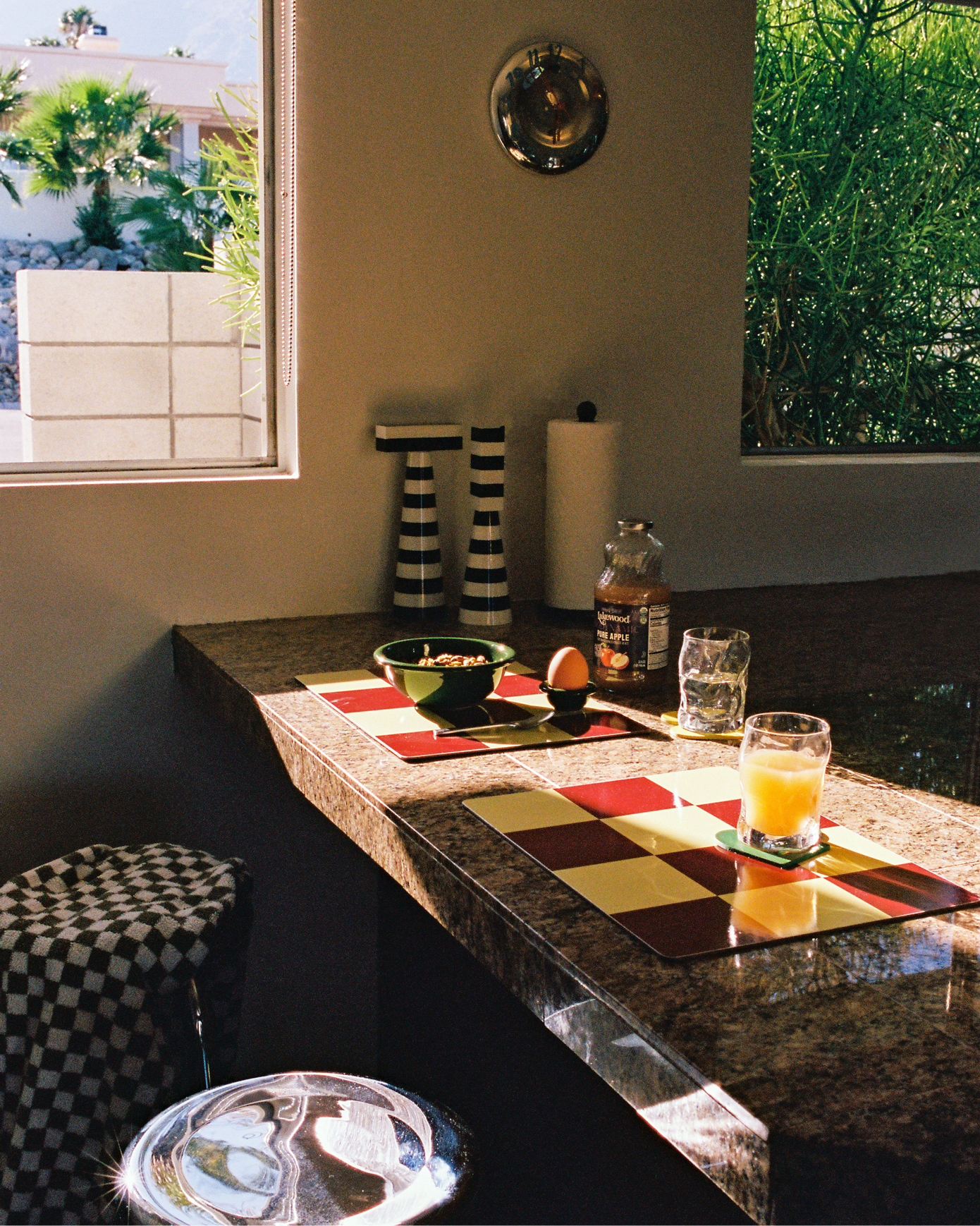 A lifestyle image of a kitchen scene featuring Speculo Wall Clock, Check Placemats, Bronto Bowl, Bronto Egg Cup, Molino Grinders, and Disco Coasters.