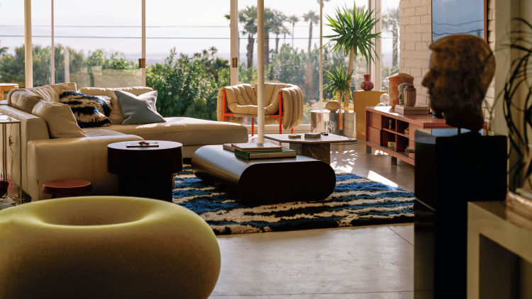 A lifestyle image of a living room/lounge scene featuring Puffy Lounge Chair Sand/Traffic Red, Monster Rug, Stump Coffee Table Large, Stump Side Table, Boa Pouf Sulfur Yellow, Velvet Cushion Medium, and Monster Cushion Medium.