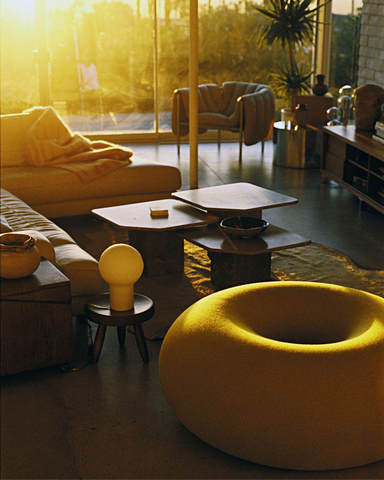 A lifestyle image of a living room / lounge scene featuring Puffy Lounge Chair, Coco Table Lamp, Monster Throw, and Boa Pouf.