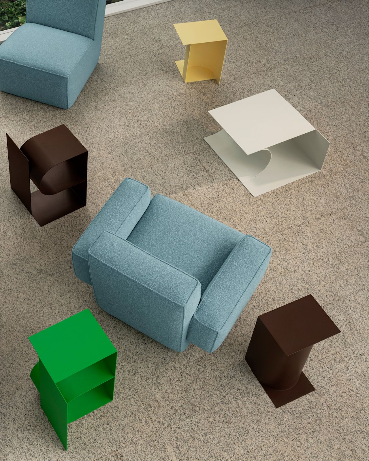 A lifestyle image of a lounge scene featuring Hunk Lounge Chairs and Glyph Side Tables.