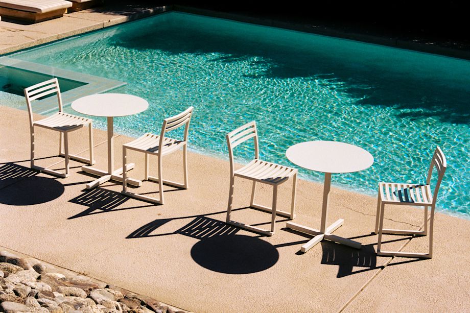 A lifestyle image of an outdoor patio scene featuring Chop Round Table and Chop Chairs in Grey White.