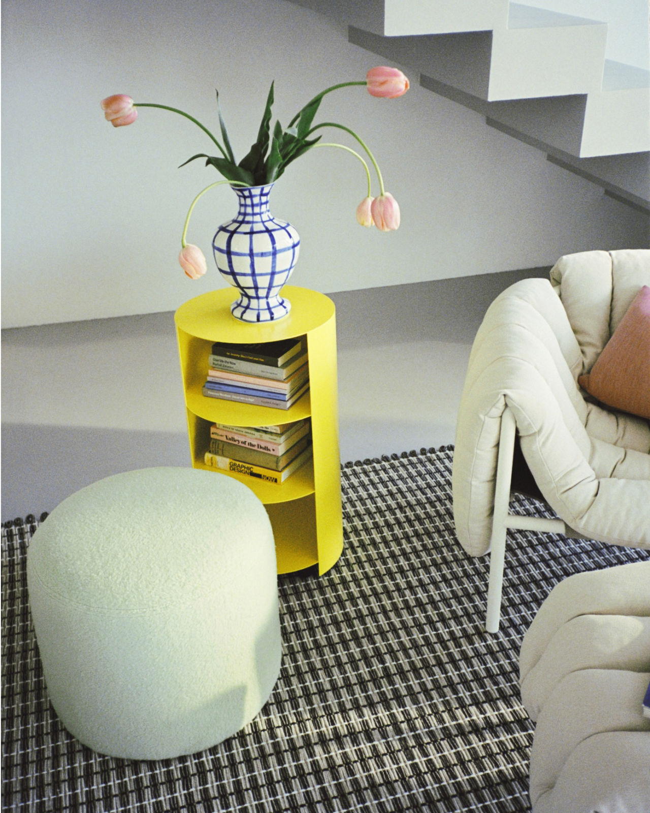 An analog image of a lounge scene featuring Rope Rug, Hide Pedestal, Bon Pouf Round, Neo Cushion, and Puffy Lounge Chair + Ottoman.