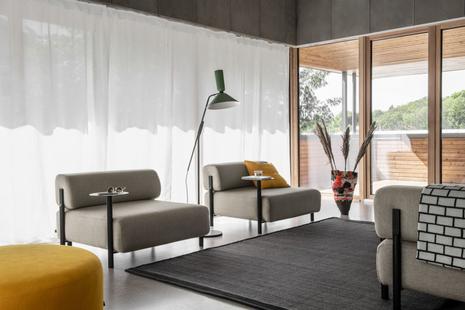 A lifestyle image of a living room scene featuring Palo Modular Sofa, Brick Throw, Bon Pouf Round Large, Alphabeta Floor Lamp, and Dune Rug.