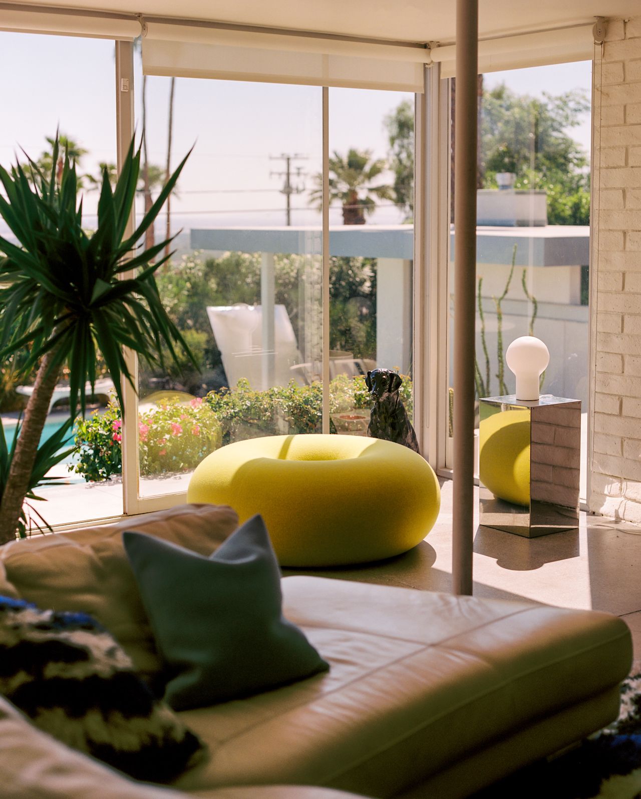 A lifestyle image of a lounge scene featuring Boa Pouf Sulfur Yellow, Coco Table Lamp, and Velvet Cushion Medium Light Blue.