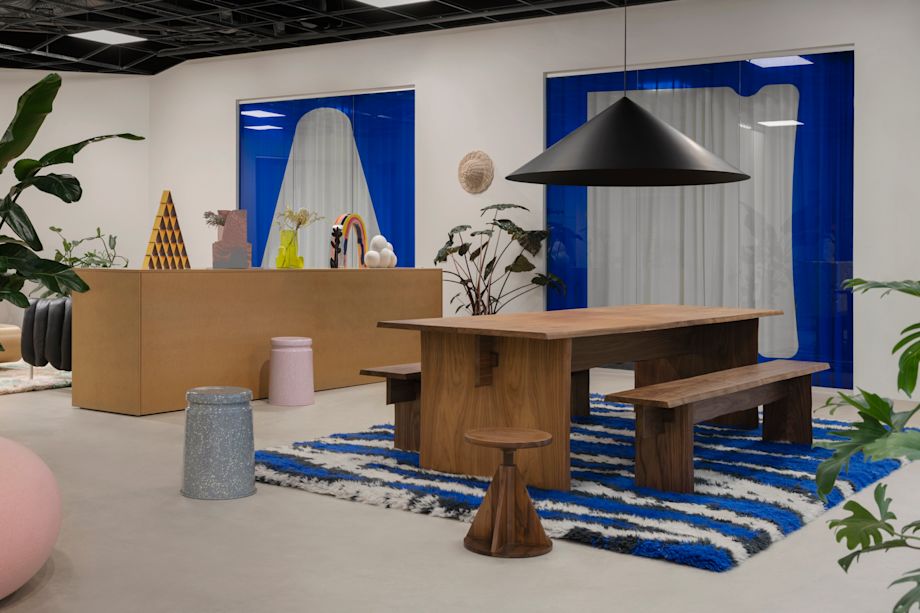 A lifestyle image from Hem's Stockholm headquarters featuring Bookmatch Table + Benches Set, Monster Rug, All Wood Stool, Last Stool, Boa Pouf, and more.