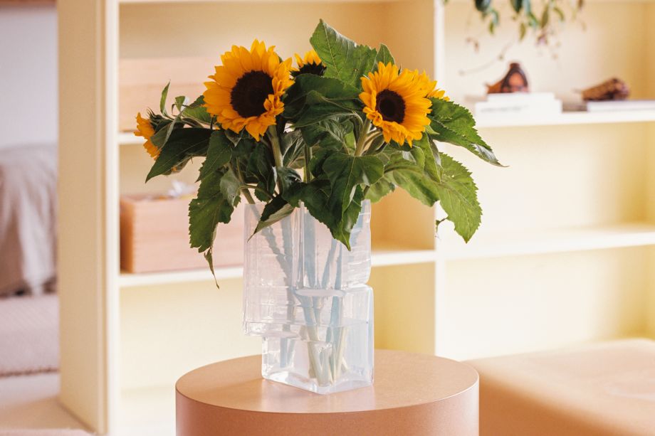 A lifestyle image of a lounge scene featuring Brute Vase Opal White on top of a Stump Side Table Natural.