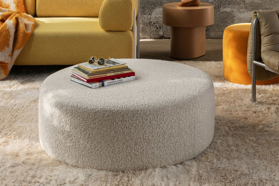 Lifestyle image of a living room scene featuring Bon Pouf Round Large in Eggshell and Monster Rug.