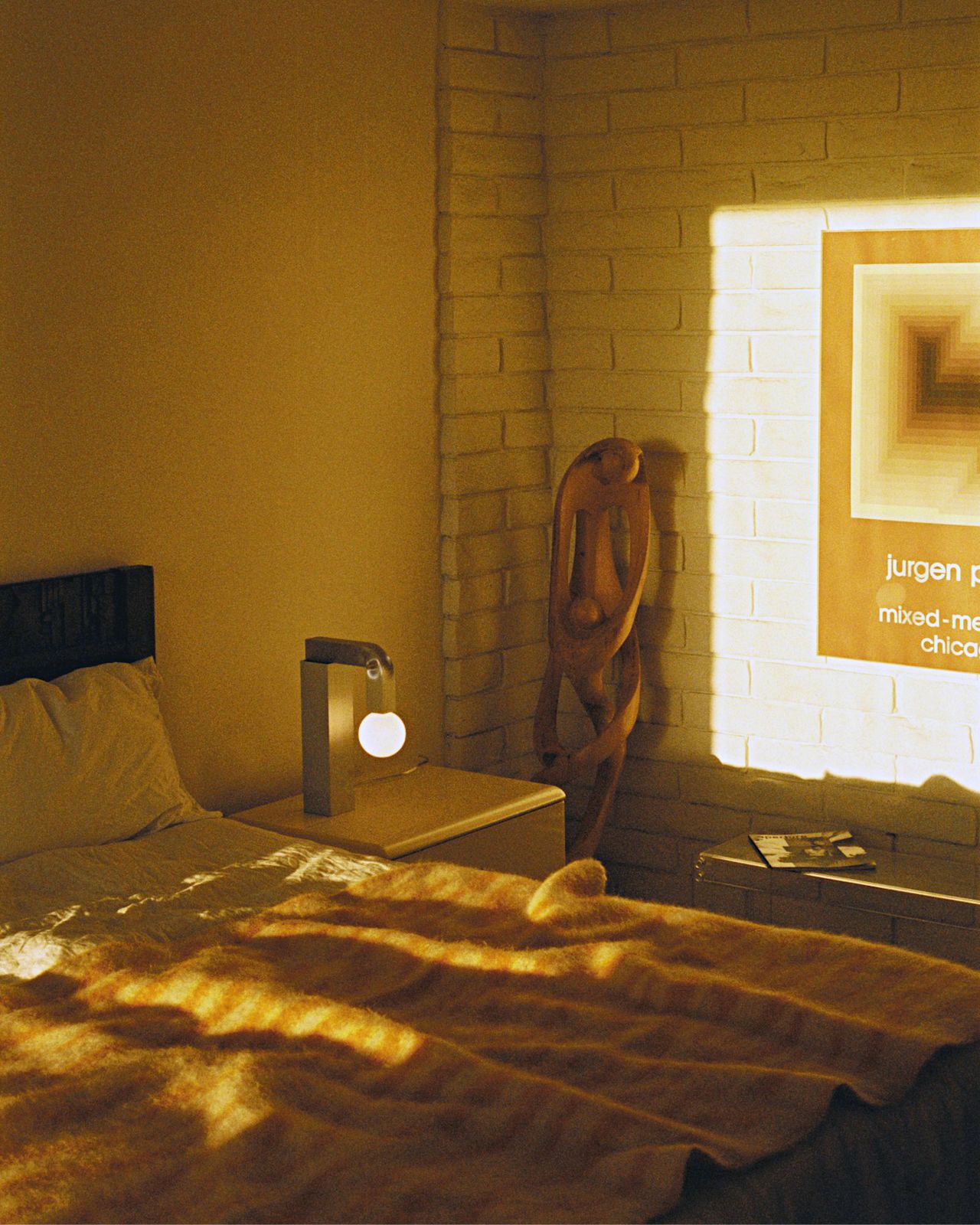 A lifestyle image of a bedroom scene featuring Knuckle Table Lamp and Monster Throw.