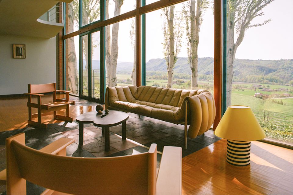 A lifestyle image of a lounge scene featuring Puffy Sofa, Toto Table Lamp, Bullnose Lounge Chair, and Worm Table.