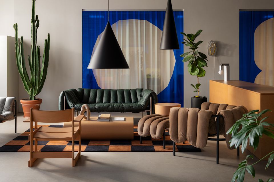 An editorial image from Hem's Stockholm HQ featuring Puffy Lounge Chair, Puffy Sofa, Stump Side Table, Stump Coffee Table Large, Knuckle Table Lamp, Globos Neon, and Pattern Rug.