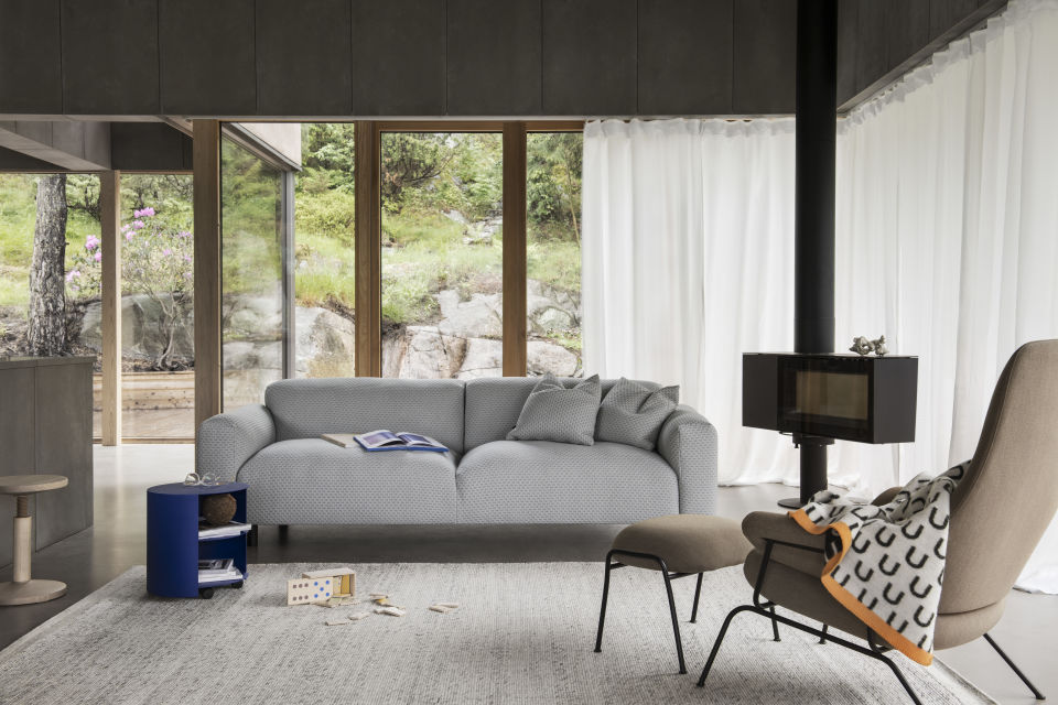 A lifestyle image of a living room/lounge scene featuring Koti Sofa, Dune Rug, Hide Side Table, Hai Lounge Chair + Ottoman, All Wood Stool, Arch Throw, and Dash Cushions.