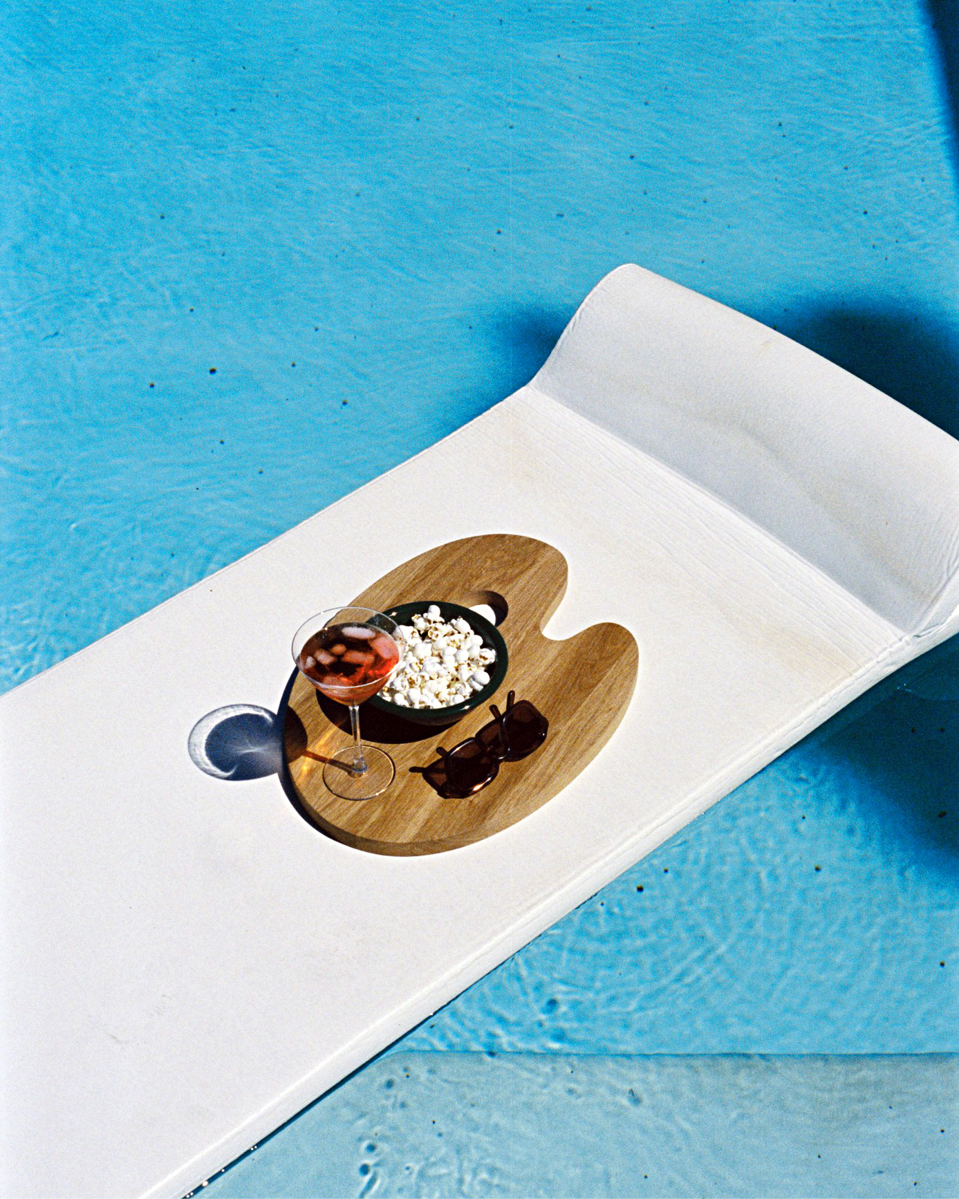 A lifestyle image of an outdoor pool scene featuring Palette Cutting Board.