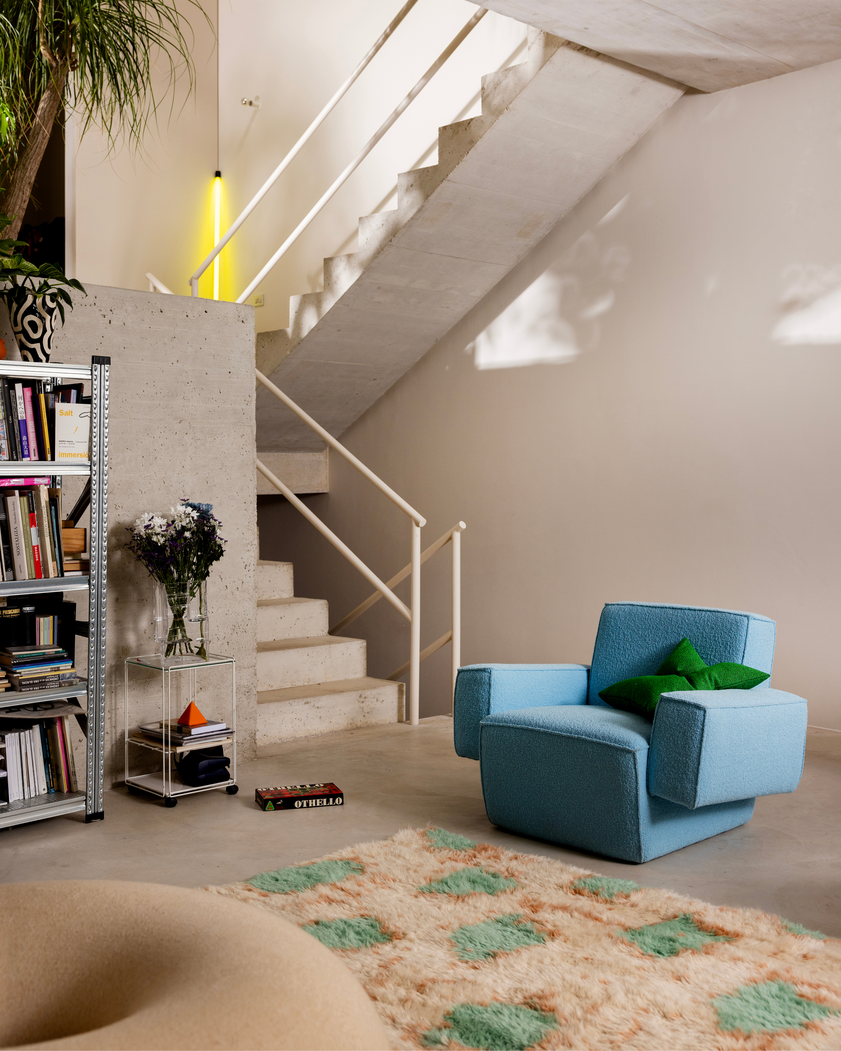 A lifestyle image of a lounge scene featuring Hunk Lounge Chair with Armrests, Crepe Cushion Medium, and Monster Rug.