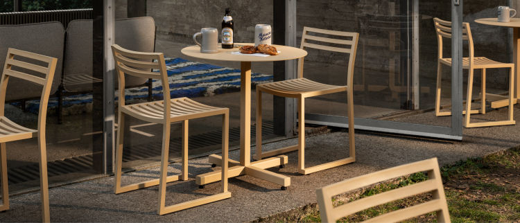 A lifestyle image of an outdoor scene featuring Chop Chairs and Chop Table Round.