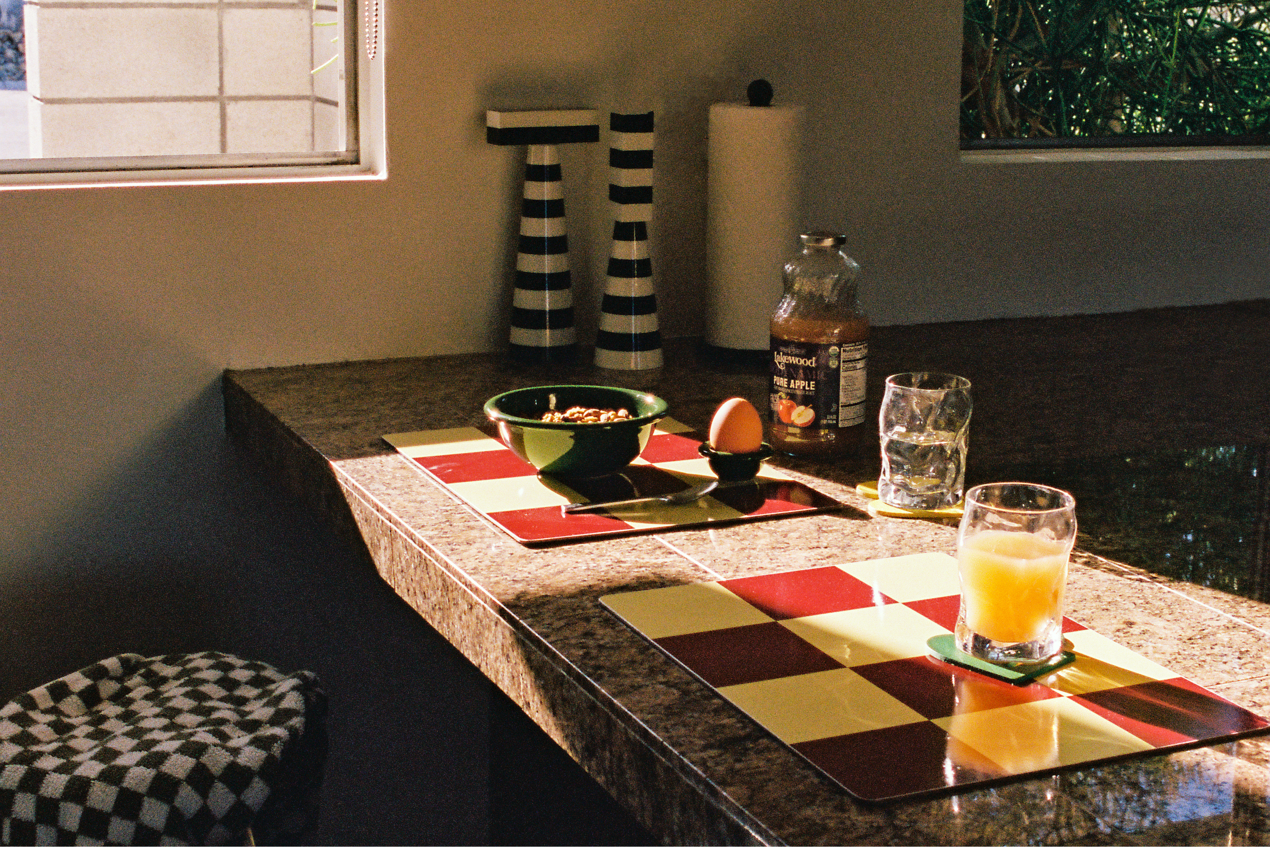 A lifestyle image of a kitchen scene featuring Check Placemats, Molino Grinders, Bronto Bowl, and Bronto Egg Cup.